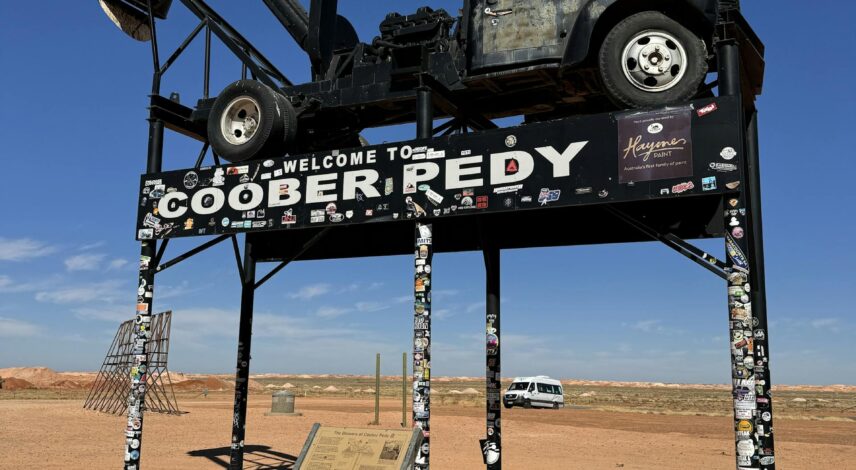 A vintage truck displayed atop a sign welcomes visitors to Coober Pedy, an iconic Australian opal mining town.
