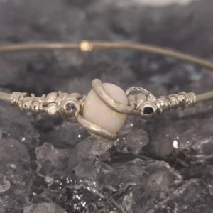 Alishia cuff with 2.30 ct oval Coober Pedy natural white opal, hand-wrapped in cool-toned 925 silver, shimmering blue, green, pink, orange, and gold flashes.